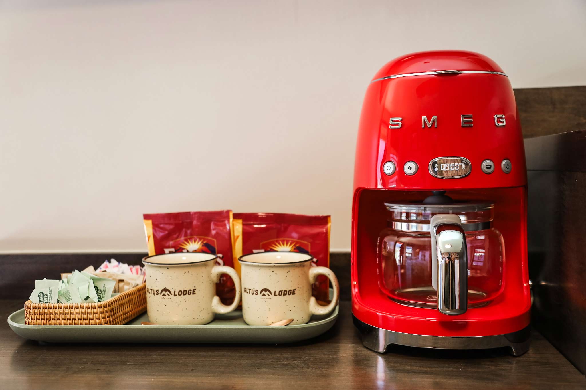 A view of a SMEG coffee maker and Altus Lodge branded mugs